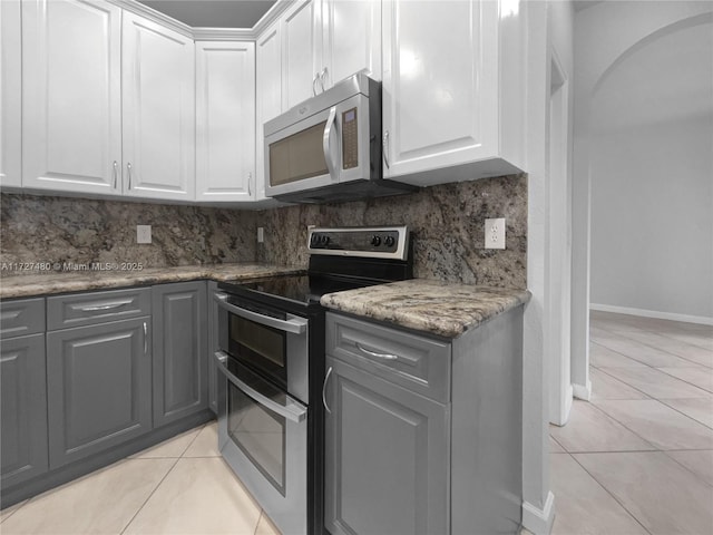 kitchen with light tile patterned floors, white cabinets, backsplash, and appliances with stainless steel finishes