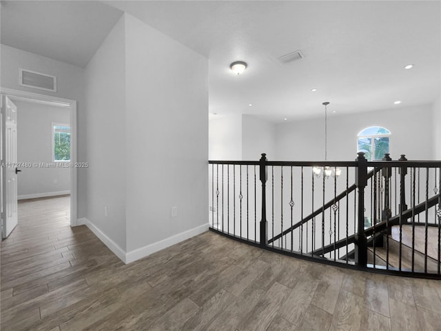 hallway with plenty of natural light, wood-type flooring, and an inviting chandelier