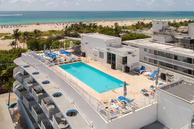 view of pool with a patio area, a water view, and a view of the beach