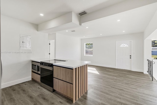 kitchen with kitchen peninsula, electric panel, electric range oven, and hardwood / wood-style flooring