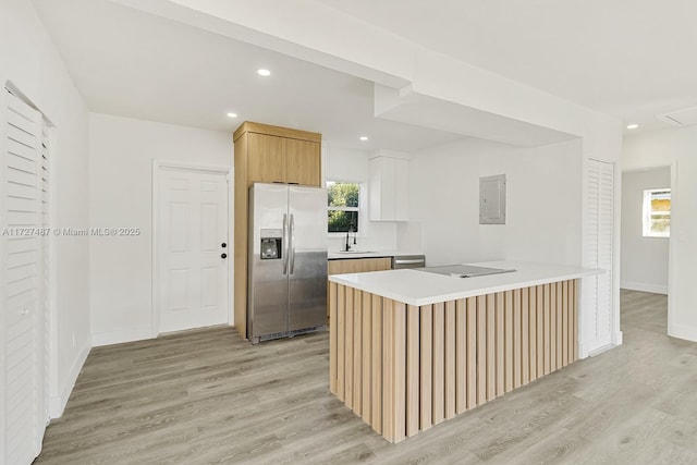 kitchen with electric panel, sink, light wood-type flooring, appliances with stainless steel finishes, and white cabinets