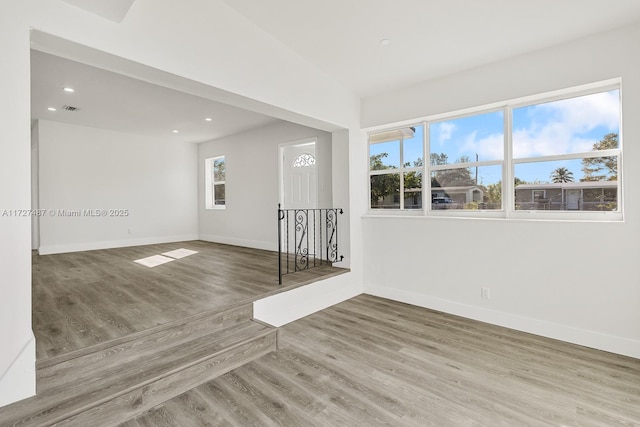 spare room featuring lofted ceiling and hardwood / wood-style floors