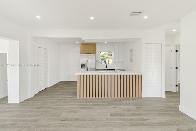 kitchen featuring stainless steel fridge with ice dispenser, light wood-type flooring, and sink