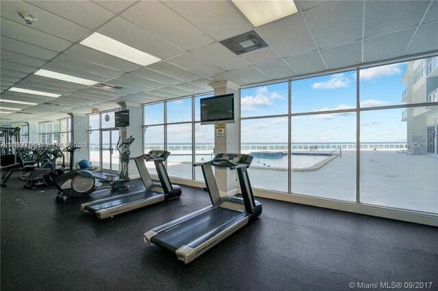 gym with a paneled ceiling and a wall of windows