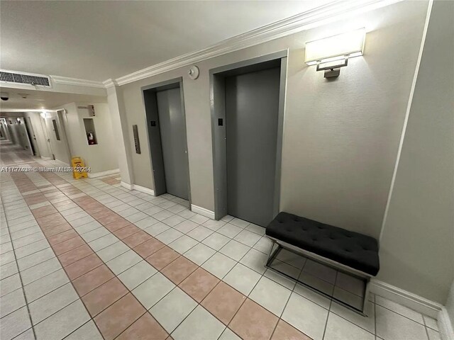 hallway with crown molding, elevator, and light tile patterned flooring