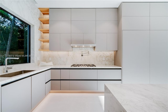 kitchen with white cabinets, decorative backsplash, sink, and light stone counters