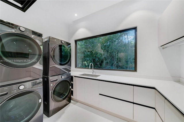 laundry area with stacked washer / drying machine, sink, and cabinets