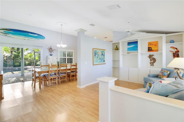 living room featuring ceiling fan with notable chandelier, hardwood / wood-style flooring, and built in shelves