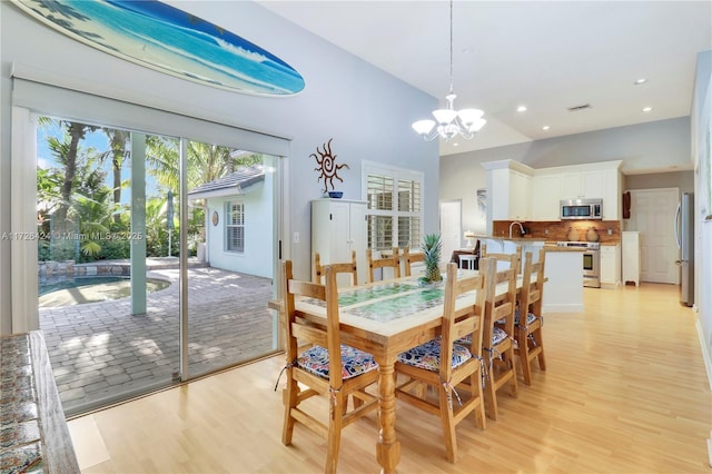 dining space with sink, light hardwood / wood-style flooring, and a notable chandelier