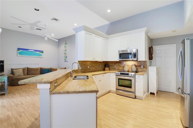 kitchen featuring kitchen peninsula, ceiling fan, appliances with stainless steel finishes, tasteful backsplash, and sink