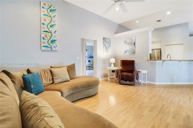 living room featuring ceiling fan, sink, lofted ceiling, and light wood-type flooring