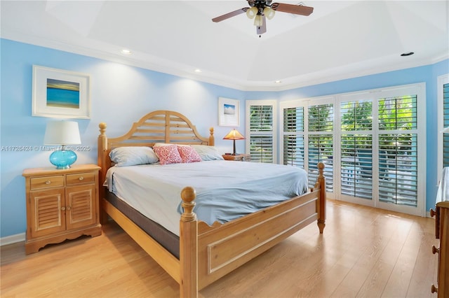 bedroom with ceiling fan, light hardwood / wood-style floors, and a raised ceiling