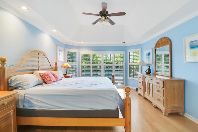 bedroom with a raised ceiling, ceiling fan, ornamental molding, and light hardwood / wood-style floors