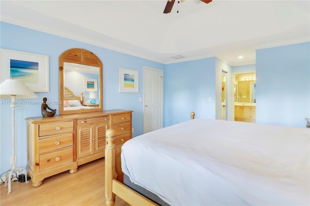 bedroom featuring ceiling fan, crown molding, ensuite bath, and light wood-type flooring