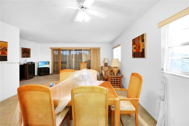 carpeted dining room with a textured ceiling, ceiling fan, and a wealth of natural light