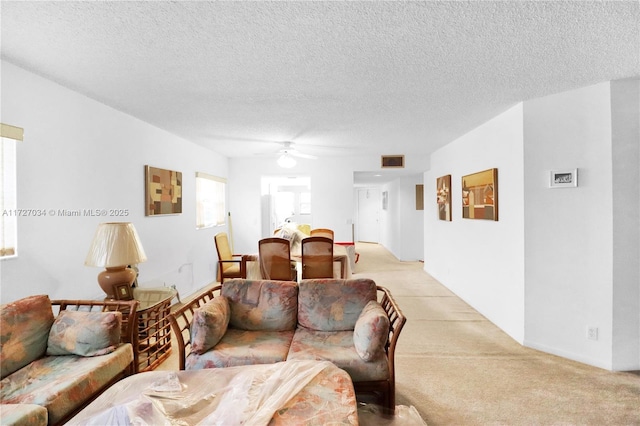 carpeted living room with a textured ceiling and ceiling fan