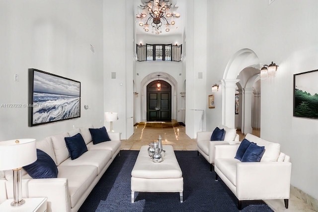 living area with a high ceiling, arched walkways, a notable chandelier, and ornate columns