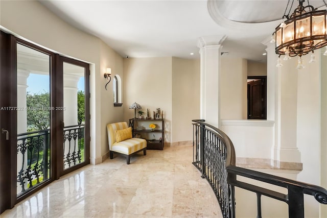 corridor featuring an inviting chandelier, ornate columns, recessed lighting, and baseboards
