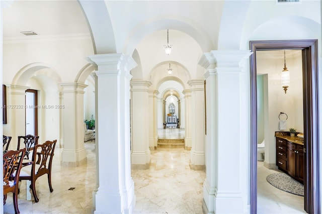 hallway with arched walkways, visible vents, and decorative columns