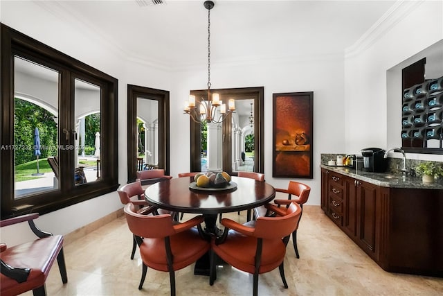 dining space featuring an inviting chandelier, sink, and crown molding