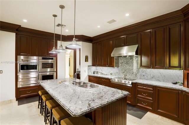 kitchen featuring built in refrigerator, exhaust hood, backsplash, and a kitchen island with sink