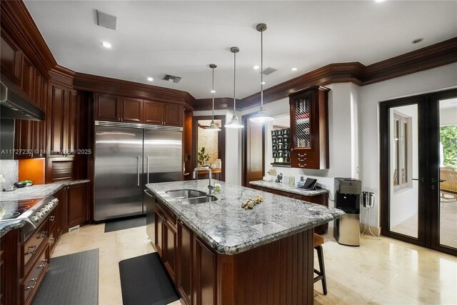 kitchen featuring exhaust hood, sink, a kitchen bar, and an island with sink