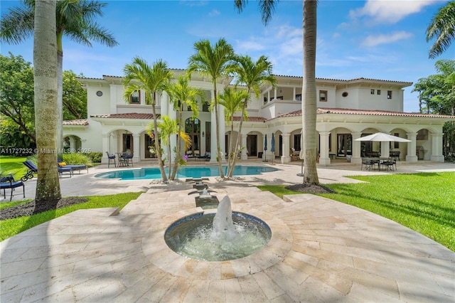 back of house with stucco siding, an outdoor pool, a tiled roof, and a patio area