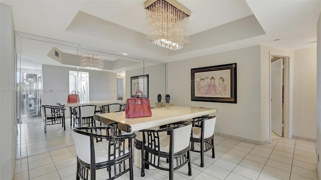 tiled dining room featuring an inviting chandelier and a raised ceiling