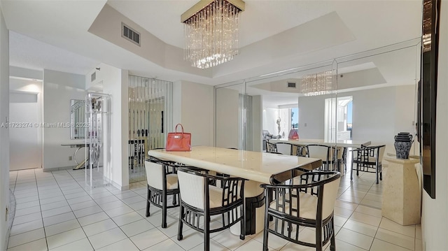 dining area featuring light tile patterned floors, an inviting chandelier, and a tray ceiling