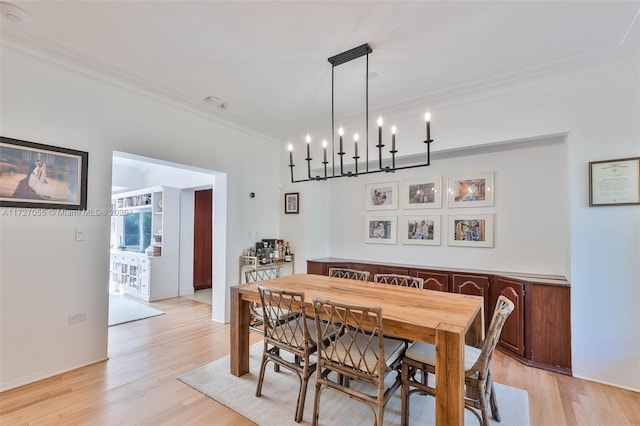 dining room with ornamental molding and light hardwood / wood-style floors