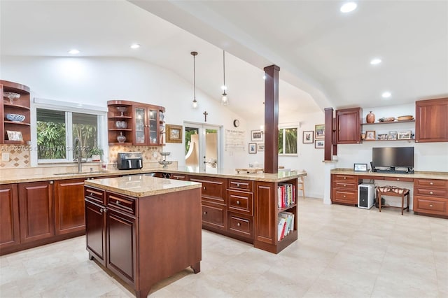 kitchen with sink, hanging light fixtures, light stone countertops, a kitchen island, and kitchen peninsula