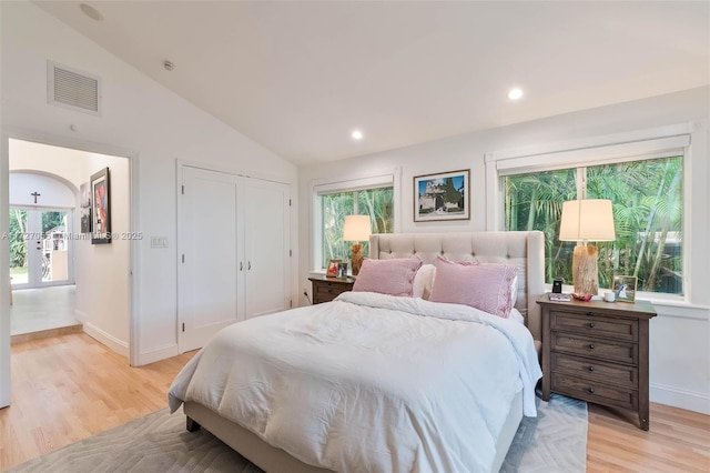 bedroom featuring vaulted ceiling, a closet, and light wood-type flooring