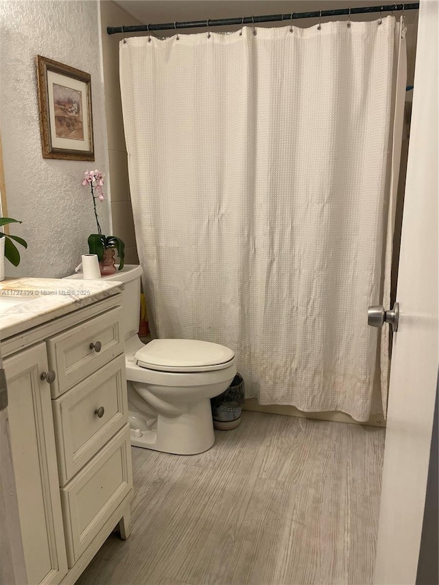 bathroom with wood-type flooring, toilet, and vanity