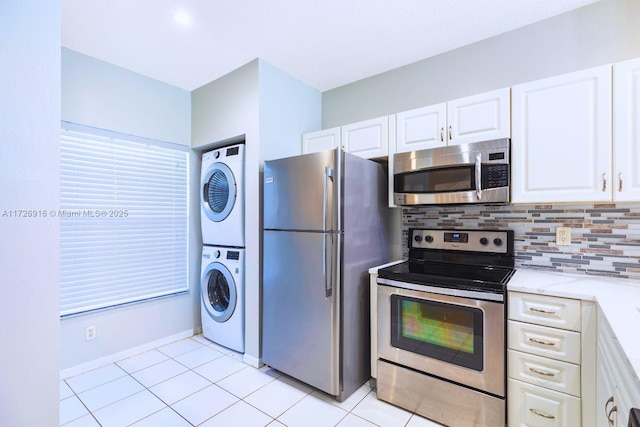 kitchen with appliances with stainless steel finishes, white cabinetry, decorative backsplash, stacked washer and clothes dryer, and light tile patterned flooring