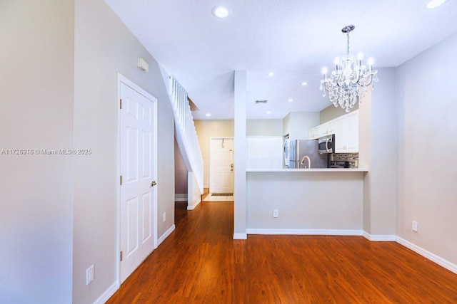 kitchen with wood finished floors, white cabinets, light countertops, freestanding refrigerator, and stainless steel microwave