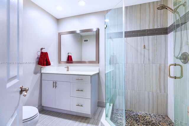 bathroom with visible vents, a stall shower, vanity, and toilet