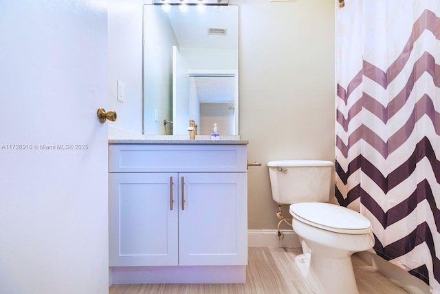 bathroom featuring a shower with shower curtain, baseboards, vanity, and toilet