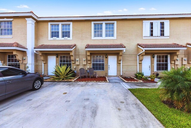 townhome / multi-family property with a tile roof and stucco siding