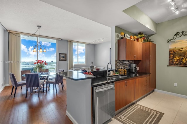 kitchen with an inviting chandelier, tasteful backsplash, sink, hanging light fixtures, and stainless steel dishwasher