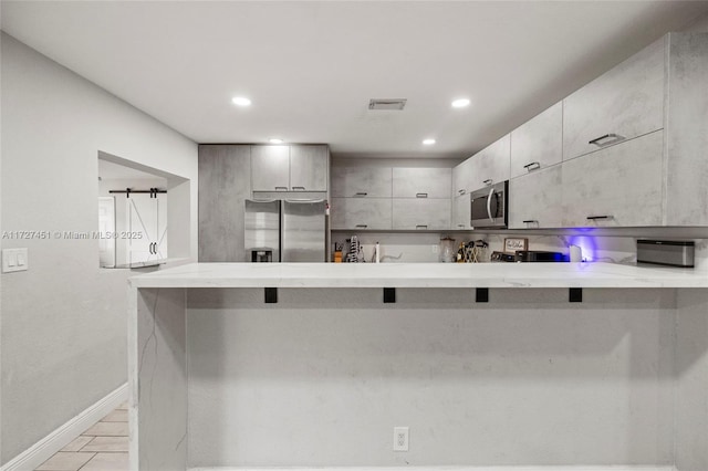 kitchen featuring appliances with stainless steel finishes, kitchen peninsula, and a breakfast bar