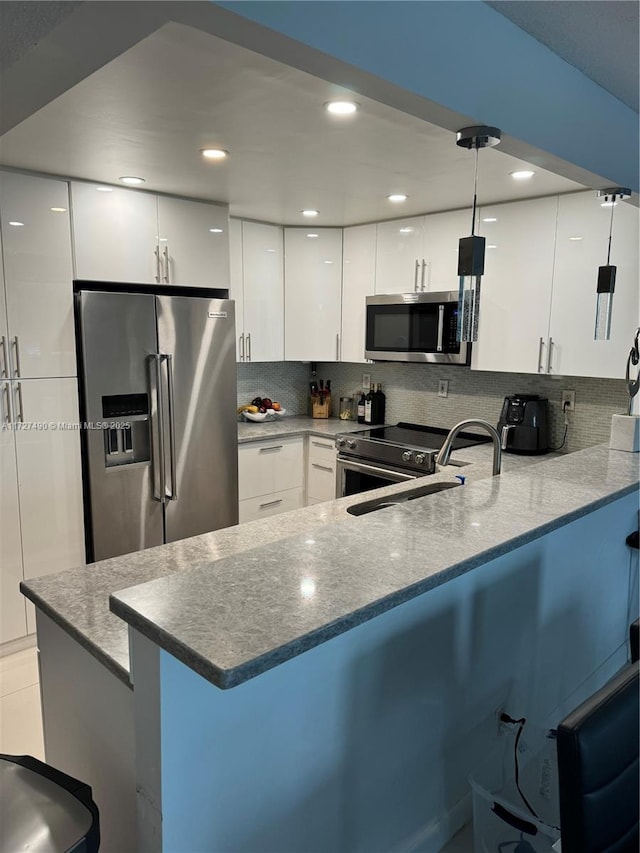 kitchen with white cabinetry, stainless steel appliances, kitchen peninsula, and decorative light fixtures