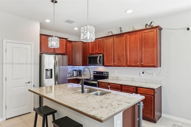 kitchen with an island with sink, stainless steel appliances, hanging light fixtures, light stone countertops, and sink