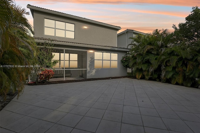 back house at dusk featuring a patio area