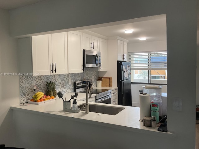 kitchen with kitchen peninsula, decorative backsplash, stainless steel appliances, and white cabinetry