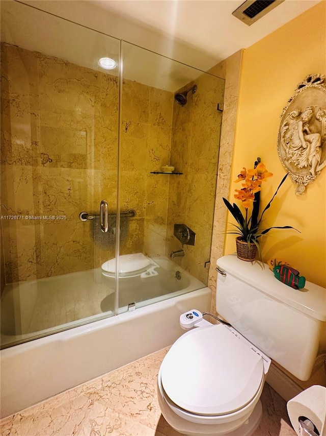 bathroom featuring combined bath / shower with glass door and toilet