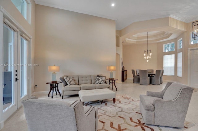 living room with a high ceiling, a tray ceiling, an inviting chandelier, and ornamental molding