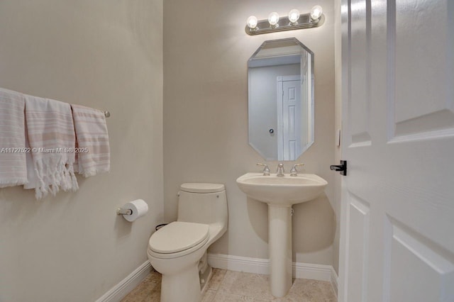 bathroom with toilet, tile patterned floors, and sink