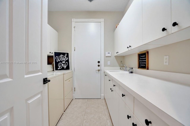 laundry room with cabinets, washer and clothes dryer, sink, and light tile patterned flooring