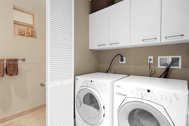 washroom featuring light tile patterned floors, washing machine and clothes dryer, and cabinets