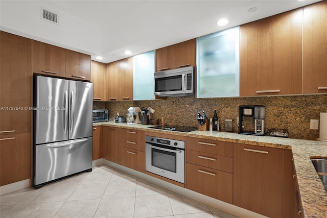 kitchen with decorative backsplash, light stone counters, appliances with stainless steel finishes, and light tile patterned flooring